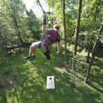 A man trying to score a goal during flying cornhole on a zipline