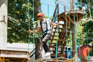A man enjoying the Refreshing Mountain ropes course on a sunny summer day.