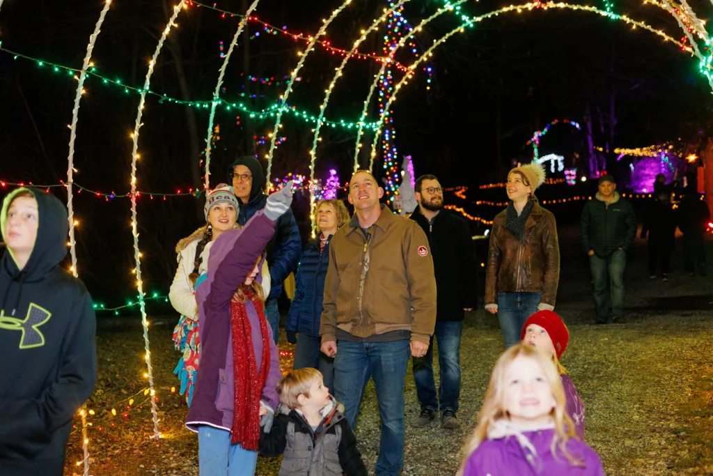 Christmas Things To Do In Lancaster, Pa: Your 2026 Holiday Guide: A Family Walking Through A Christmas Light Archway At Refreshing Mountain Retreat And Adventure Center In Lancaster, Pa.